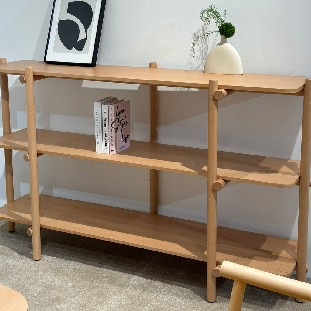 Wooden shelf with books and decor items against a plain wall COZONI