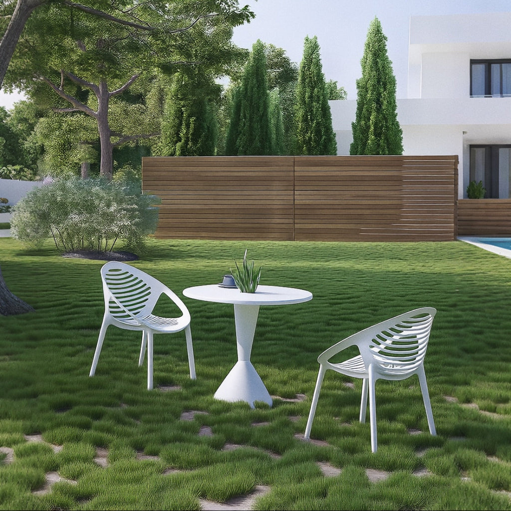 White outdoor table and chairs on a grassy lawn with a modern house in the background