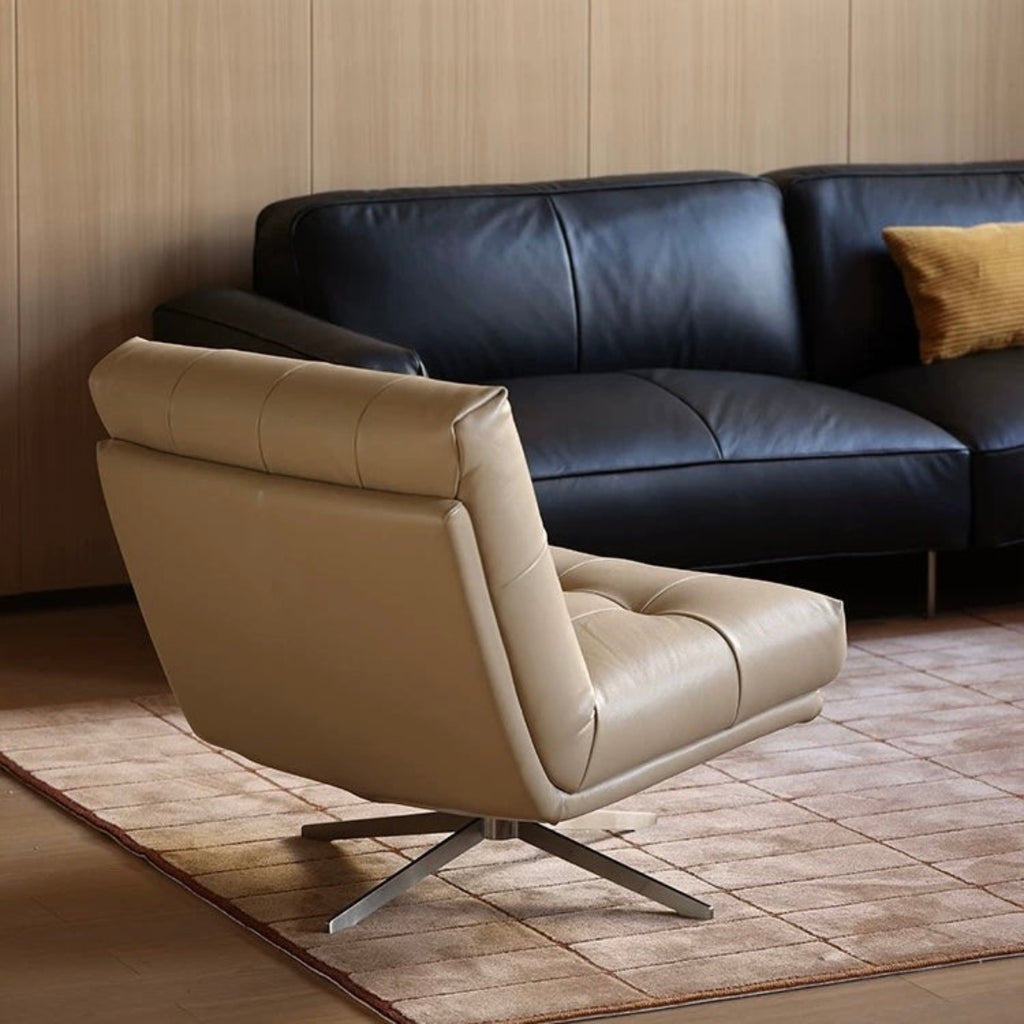 Beige armchair in front of a black leather sofa in a room with wooden flooring and walls.