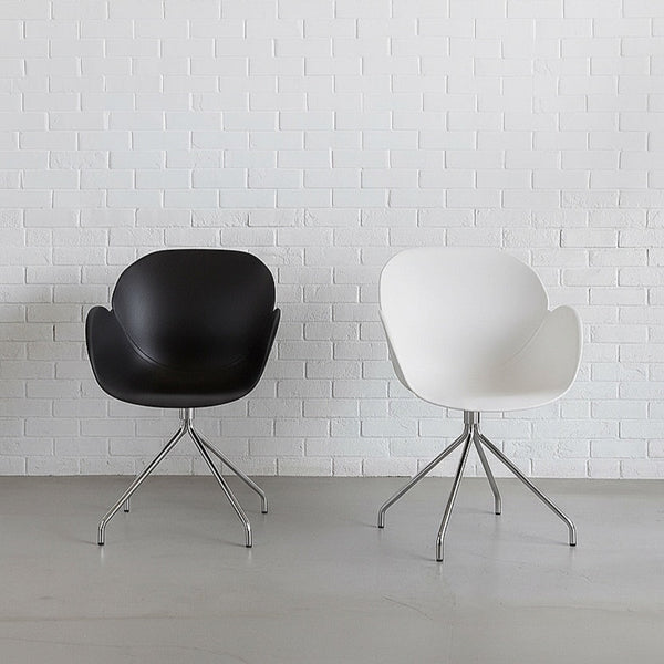 Black and white chairs with metal legs against a white brick wall.