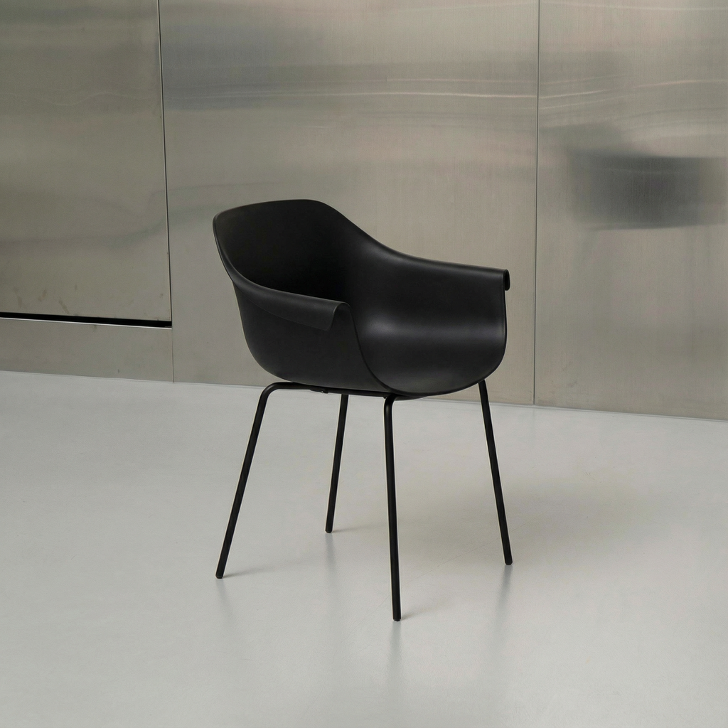 Black chair with metal legs on a white floor against a reflective wall.
