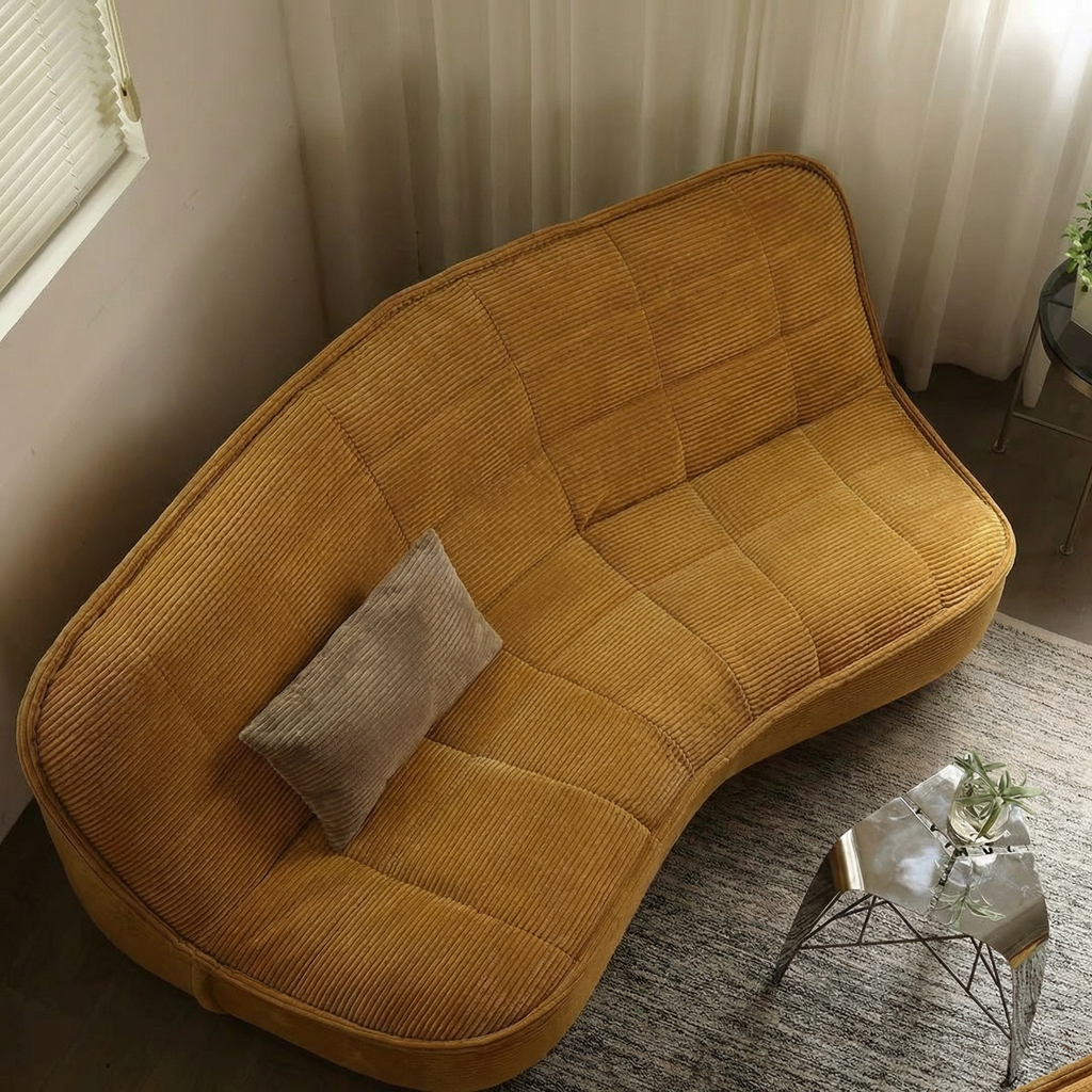 Yellow sofa with a gray pillow in a room with curtains and a small table.