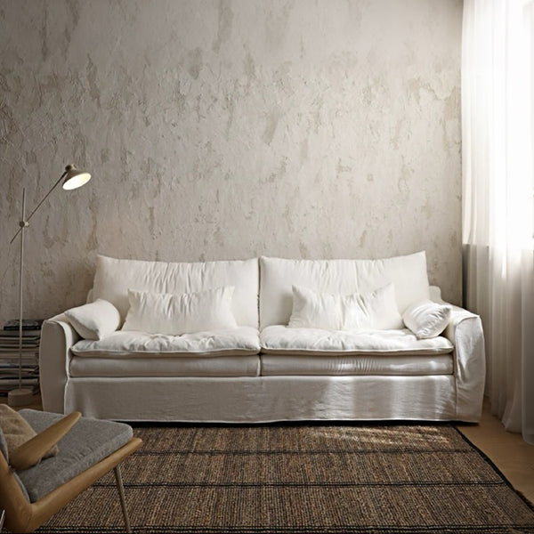 White sofa in a living room with textured wall and lamp
